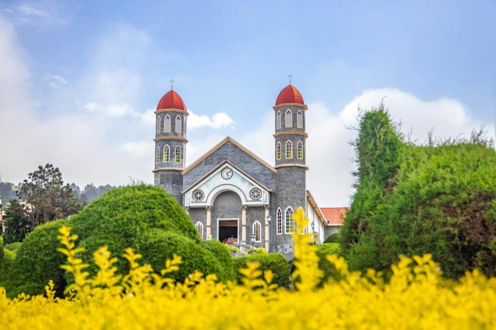 old catholic church in well maintained garden against blue sky