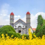 old catholic church in well maintained garden against blue sky